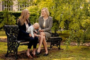 Two women and a baby sitting together on a garden bench, representing family legal support