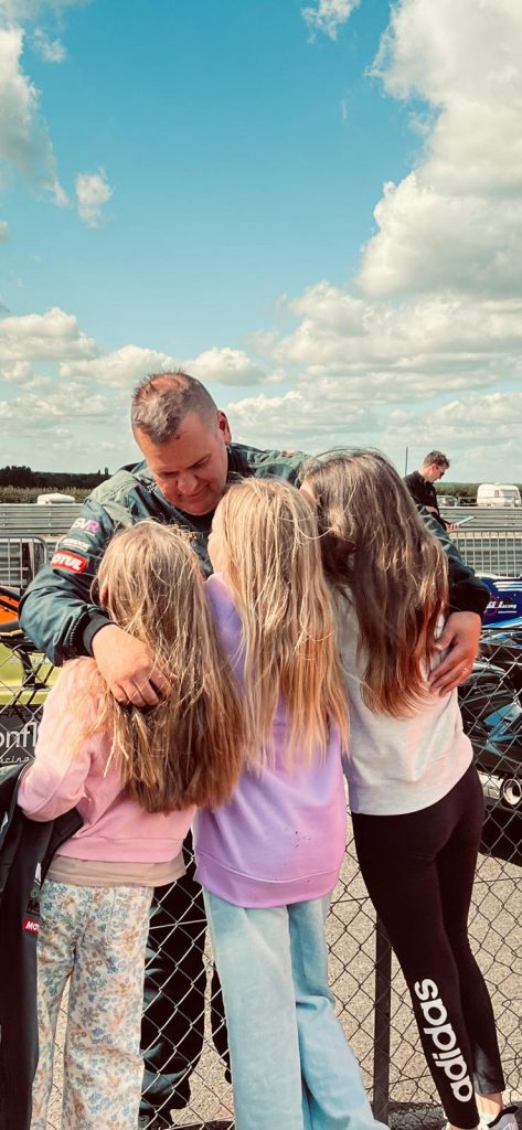 Mark Williams hugging his three daughters at an outdoor event